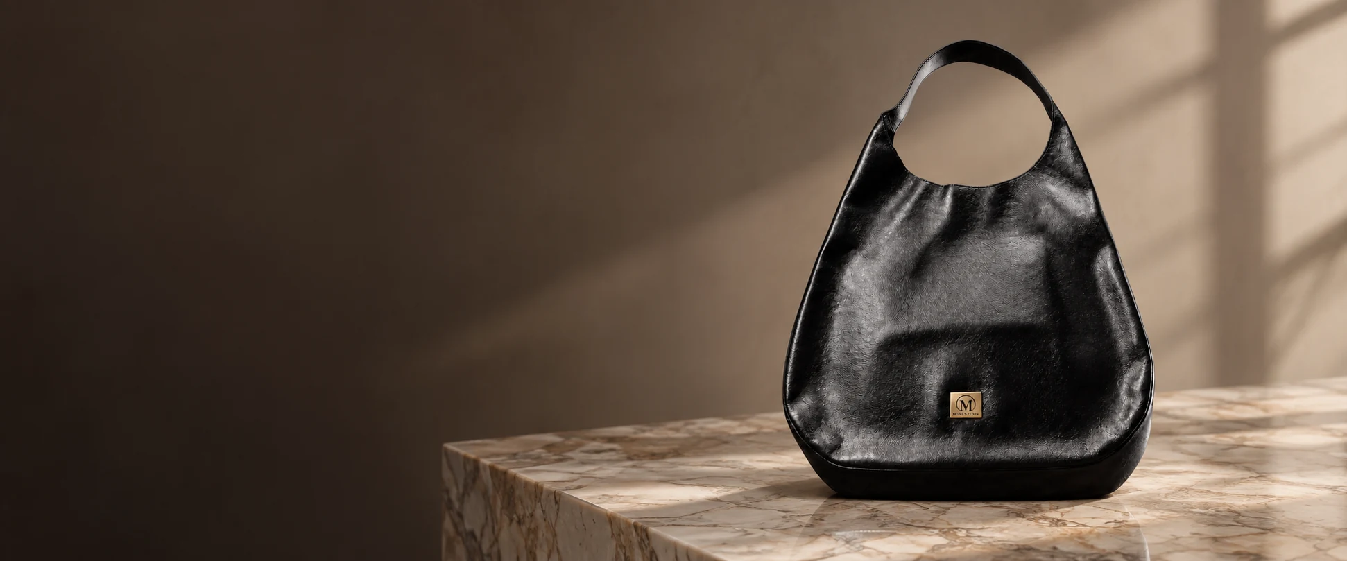 Oversized Leather Hobo Bag displayed on a marble display table against a soft taupe wall