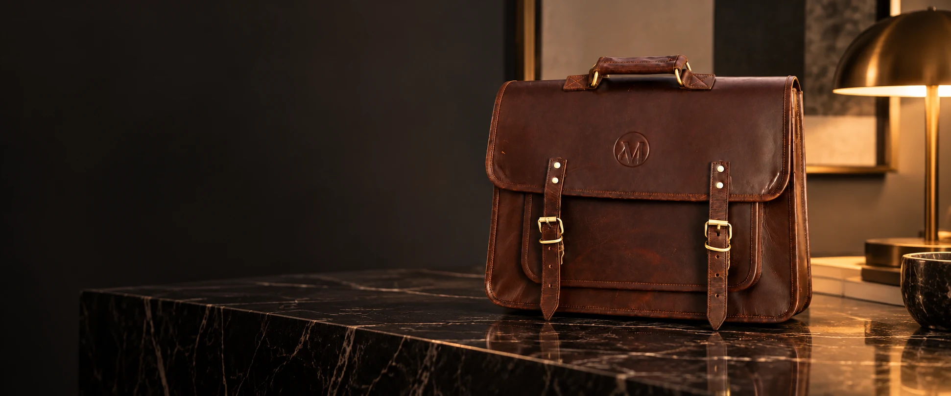 Compact Twin-Buckle Leather Messenger Bag displayed on a black marble console in a minimalist office